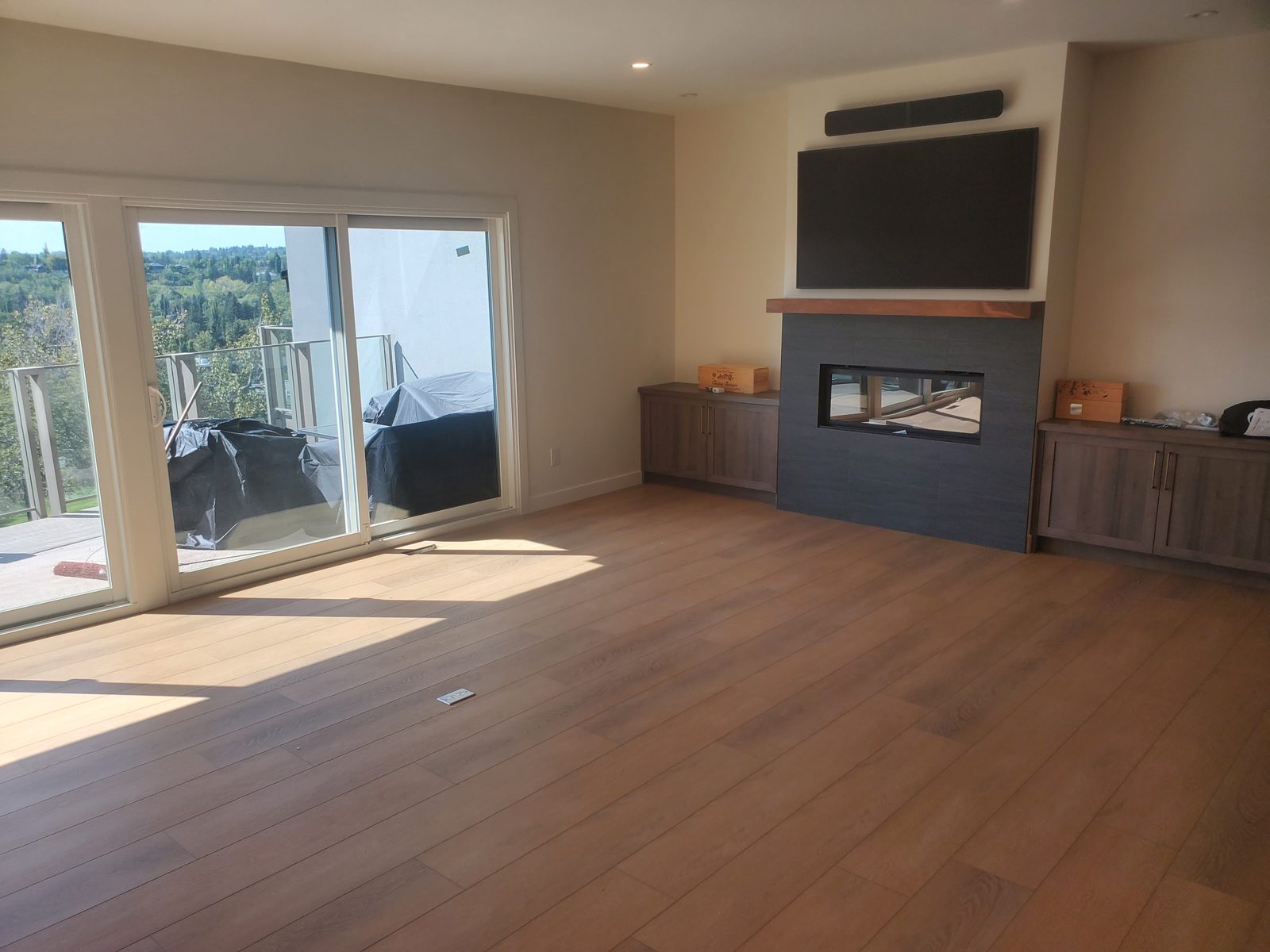 Living room fireplace wall with a mounted television and a view out to the deck