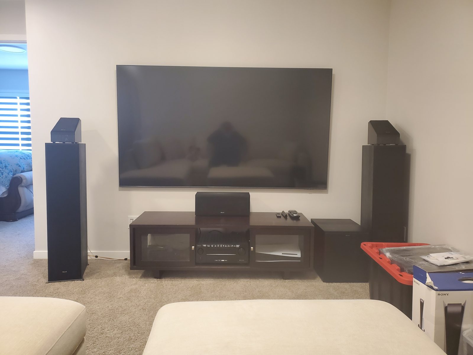 Living room with a wall-mounted television and surround speakers positioned around seating