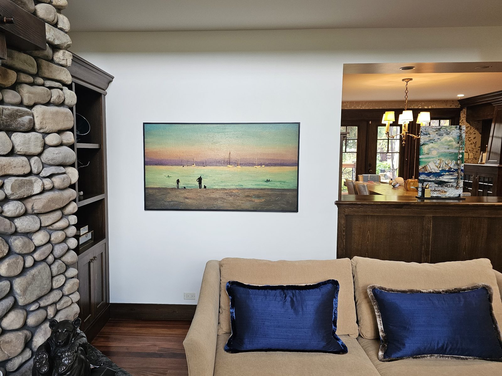 65-inch frame-style TV showing art beside a stone fireplace
