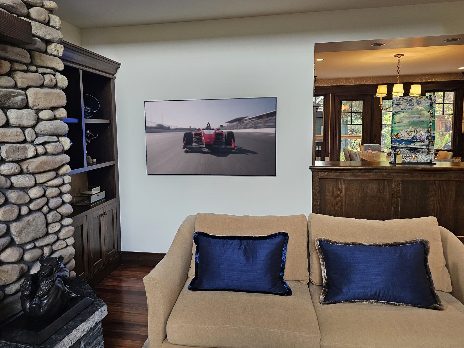 Same 65-inch frame-style TV switched on, showing motor racing