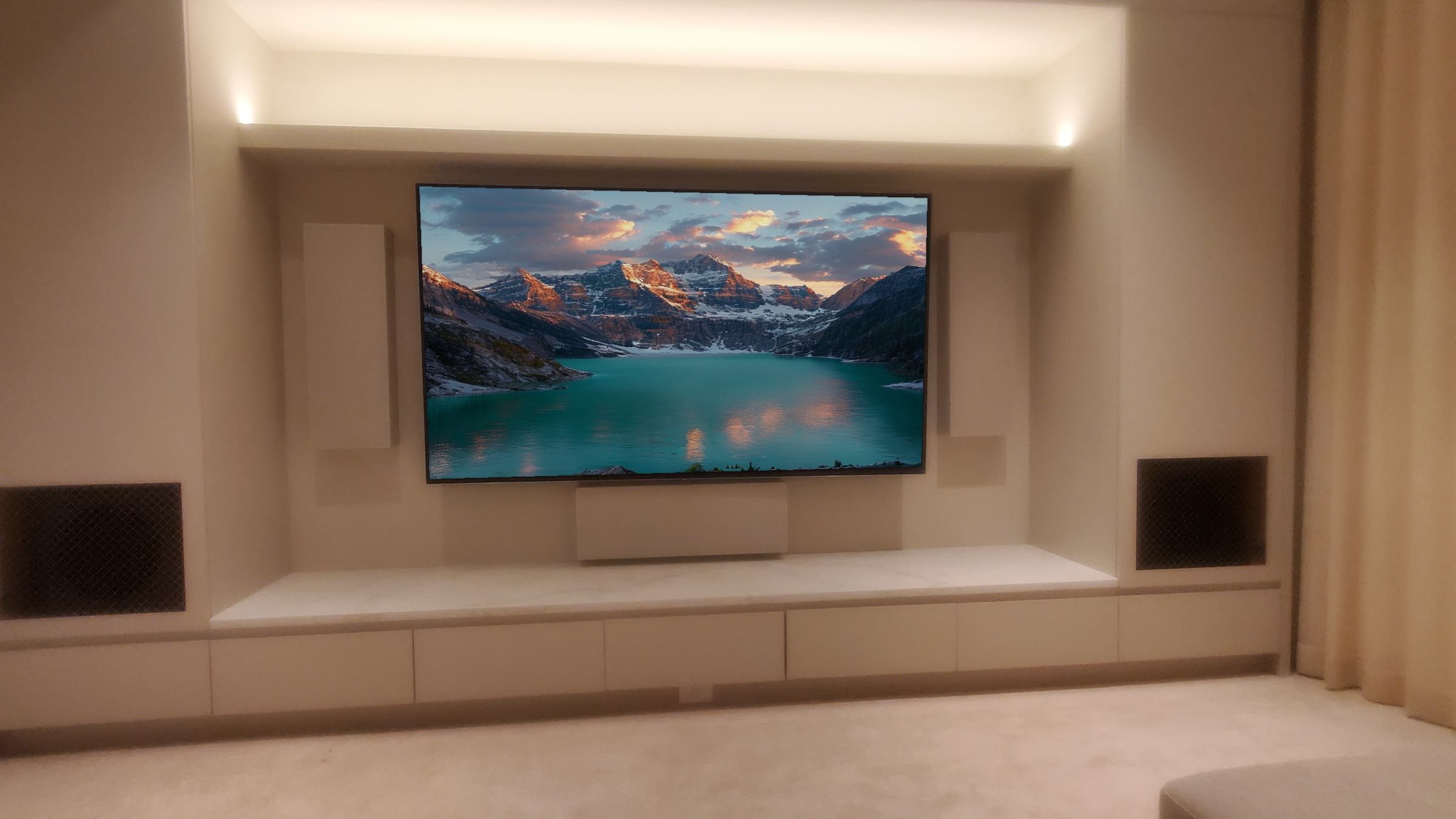 Finished Calgary media wall with concealed architectural speakers and the screen on