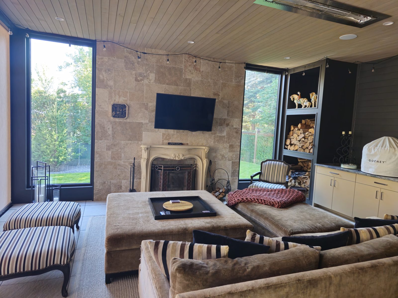 Covered outdoor patio room with a fireplace and mounted television